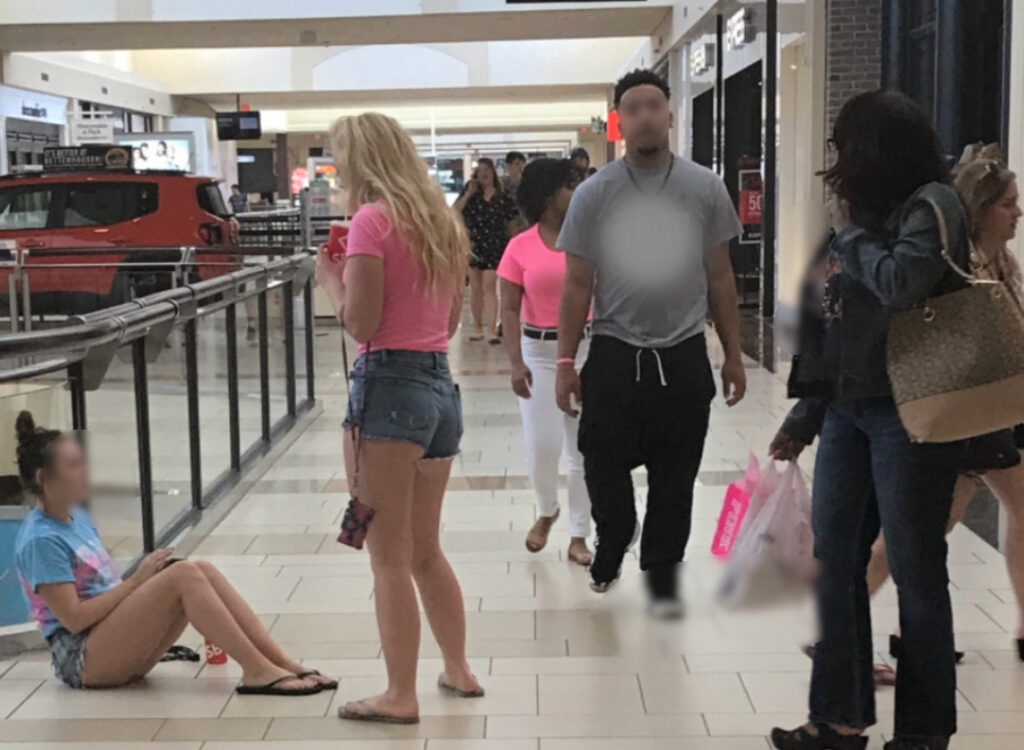 A group of people walking around in a mall.