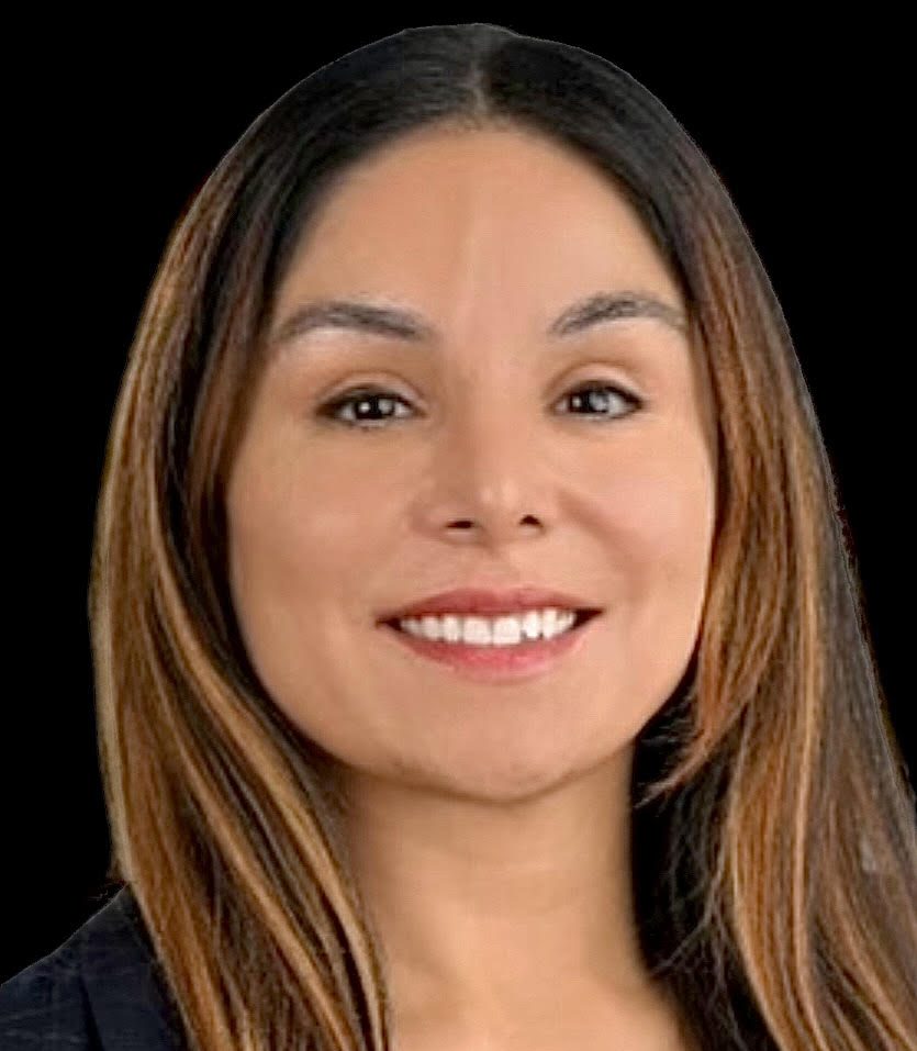 A woman with long hair and brown eyes smiling.